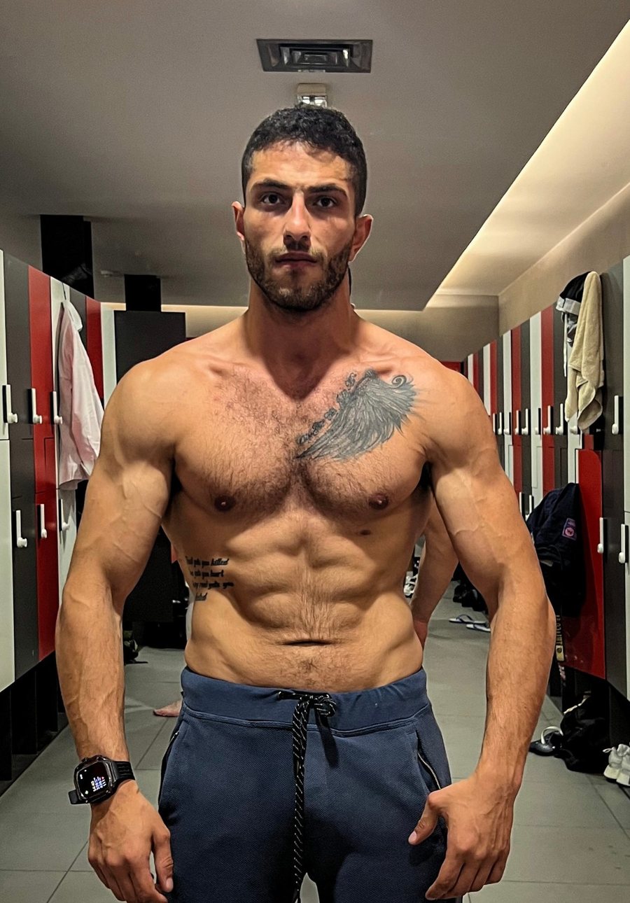 John after 12 weeks of personal training, leaner with visible muscle definition, in the same changing room